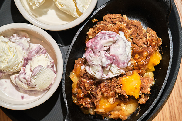 a fruit crisp topped with ice cream and 2 bowls of ice cream