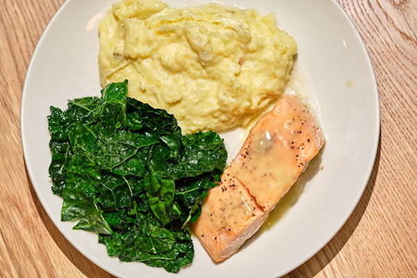 Cedar plank salmon with a side of mashed potatoes and greens