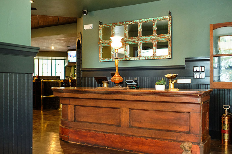 An antique bar serving as the host stand in the entrance of The Local.